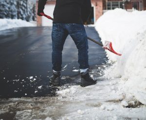 A person shovels and de-ices pavement