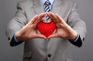 A businessman holds out a red heart