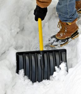 A person shovels away snow to protect their driveway.